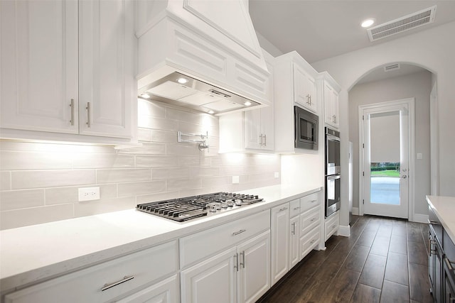 kitchen featuring stainless steel appliances, white cabinetry, premium range hood, and decorative backsplash