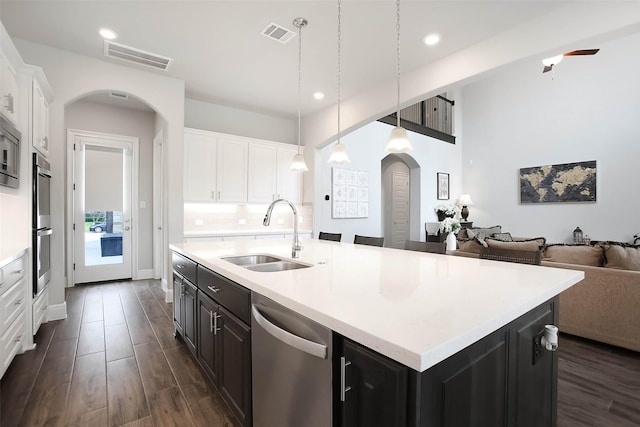 kitchen featuring sink, appliances with stainless steel finishes, white cabinets, a center island with sink, and decorative light fixtures