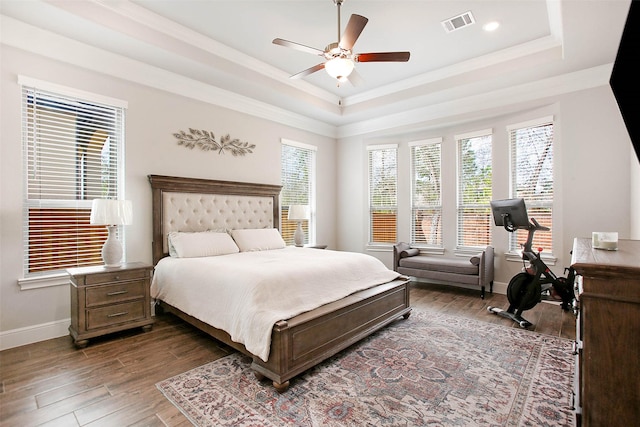 bedroom featuring multiple windows, dark hardwood / wood-style floors, crown molding, and a raised ceiling