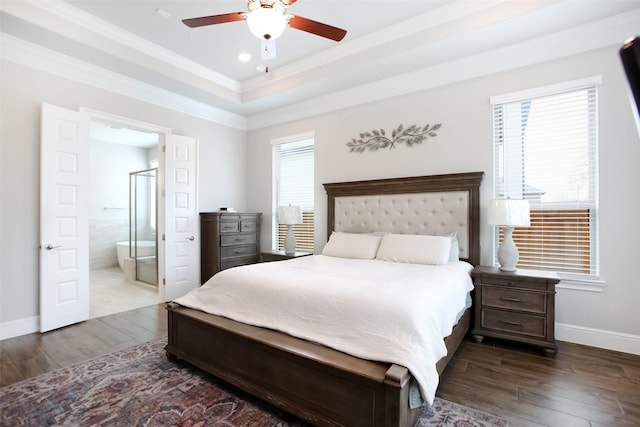 bedroom featuring crown molding, ceiling fan, connected bathroom, a tray ceiling, and dark hardwood / wood-style flooring