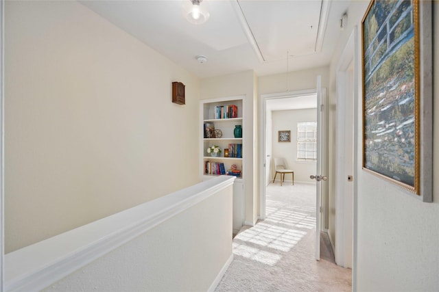 hallway featuring light colored carpet and built in features