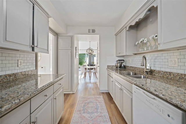 kitchen featuring sink, white cabinetry, dishwasher, light stone countertops, and light hardwood / wood-style floors