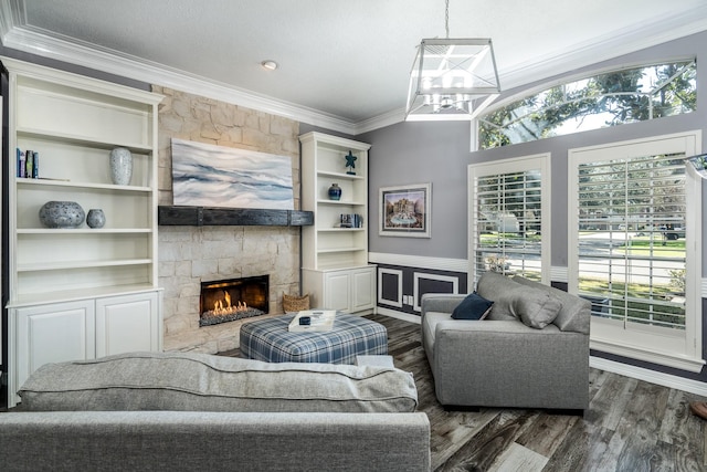 living room with dark wood-type flooring, crown molding, an inviting chandelier, a large fireplace, and built in features