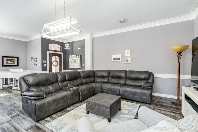 living room featuring hardwood / wood-style flooring, ornamental molding, and ornate columns