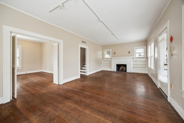 unfurnished living room featuring crown molding, rail lighting, dark hardwood / wood-style floors, and a fireplace