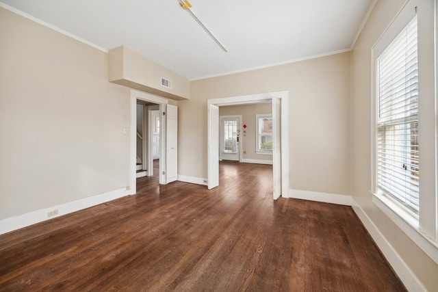 spare room featuring dark wood-type flooring and crown molding