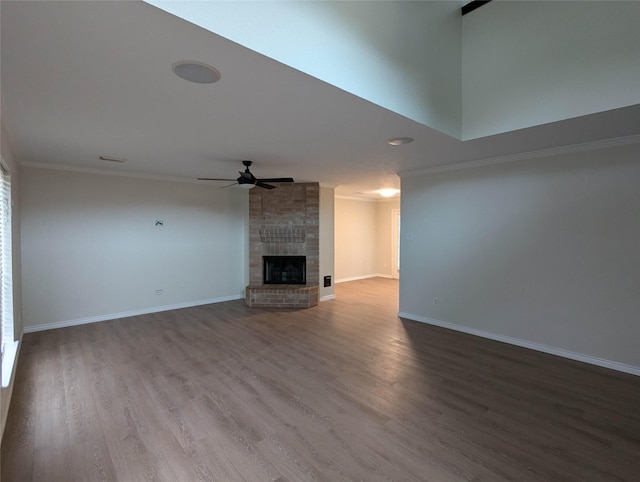 unfurnished living room with crown molding, a large fireplace, hardwood / wood-style floors, and ceiling fan