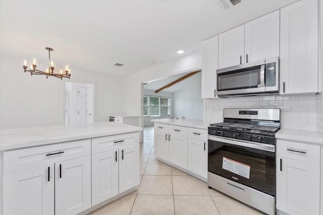 kitchen with tasteful backsplash, appliances with stainless steel finishes, white cabinets, and decorative light fixtures