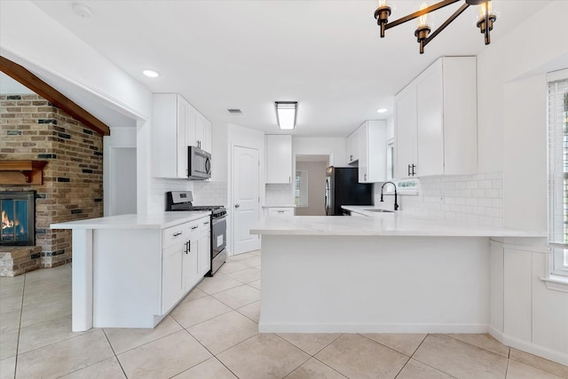 kitchen featuring white cabinetry, sink, stainless steel appliances, and kitchen peninsula