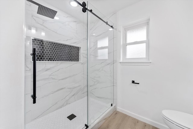 bathroom with hardwood / wood-style floors, a shower with shower door, and toilet