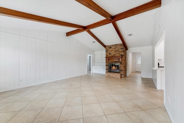 unfurnished living room featuring lofted ceiling with beams, light tile patterned floors, and a fireplace