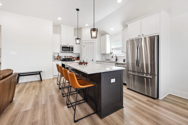 kitchen featuring a center island, decorative light fixtures, light stone countertops, appliances with stainless steel finishes, and white cabinets