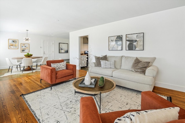 living room featuring an inviting chandelier, baseboards, and wood finished floors