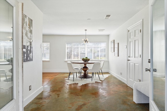 dining area with an inviting chandelier, baseboards, visible vents, and concrete flooring