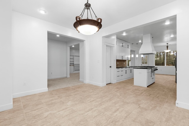 kitchen featuring hanging light fixtures, backsplash, island exhaust hood, white cabinets, and a kitchen island