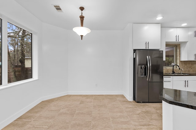 kitchen featuring stainless steel refrigerator with ice dispenser, white cabinetry, decorative light fixtures, and sink