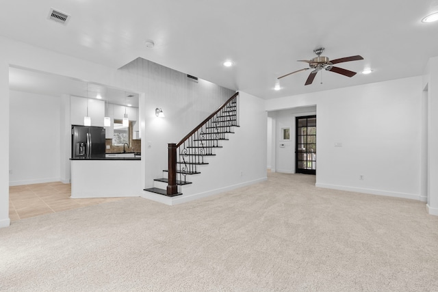 unfurnished living room featuring ceiling fan, light colored carpet, and sink