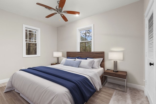 bedroom featuring ceiling fan, light wood-type flooring, and a closet