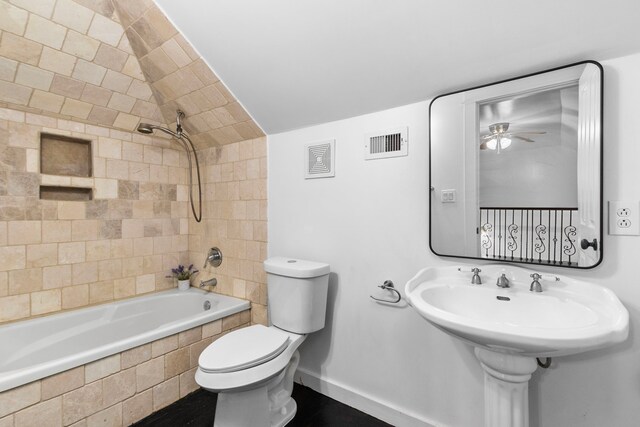 bathroom with tiled shower / bath, vaulted ceiling, ceiling fan, and toilet