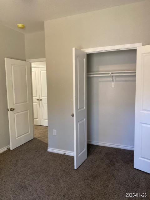 unfurnished bedroom with dark carpet and a closet