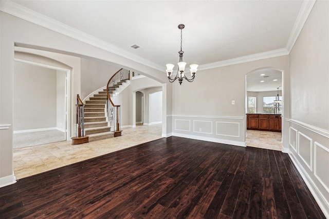 empty room with an inviting chandelier, crown molding, and wood-type flooring