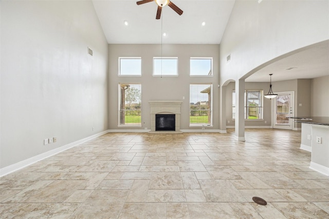 unfurnished living room featuring a towering ceiling and ceiling fan