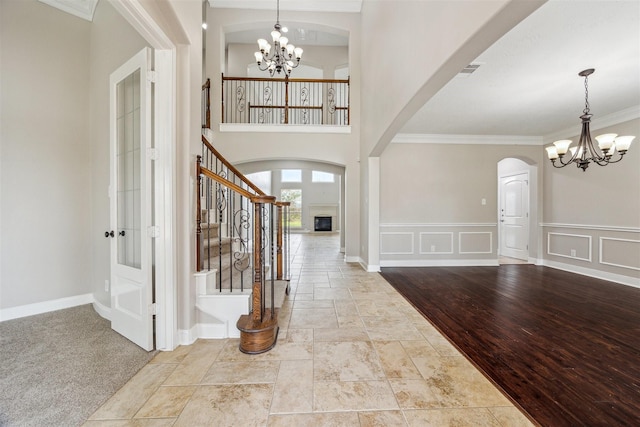 entrance foyer with ornamental molding, a towering ceiling, and an inviting chandelier