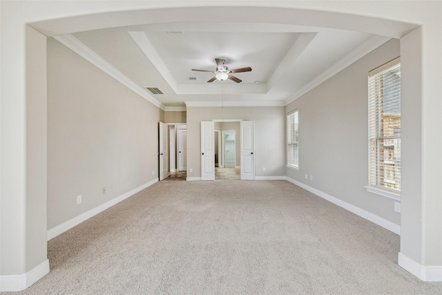 carpeted spare room featuring crown molding, ceiling fan, and a raised ceiling