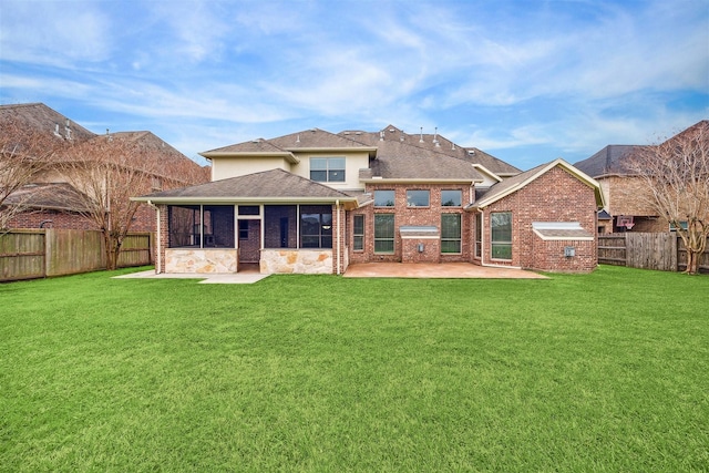 back of property with a sunroom, a patio, and a lawn