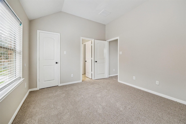 unfurnished bedroom featuring vaulted ceiling and light colored carpet