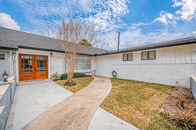 entrance to property featuring a lawn and french doors