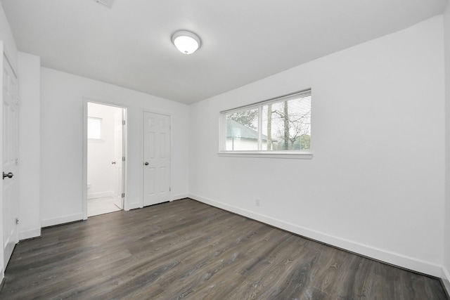 unfurnished bedroom with dark hardwood / wood-style flooring and connected bathroom