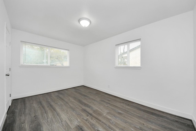 empty room with dark wood-type flooring and a healthy amount of sunlight