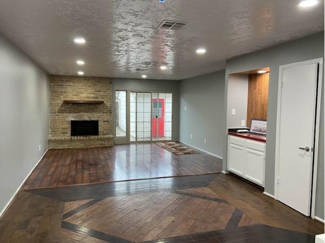 unfurnished living room with dark hardwood / wood-style flooring, a fireplace, and a textured ceiling