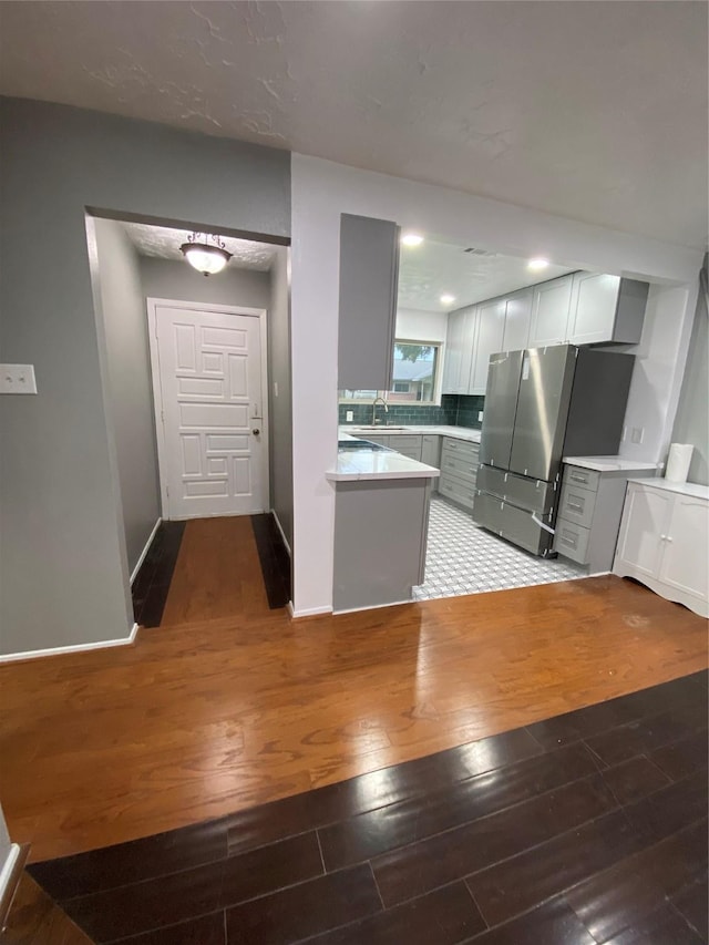 kitchen featuring hardwood / wood-style flooring, stainless steel fridge, sink, and white cabinets