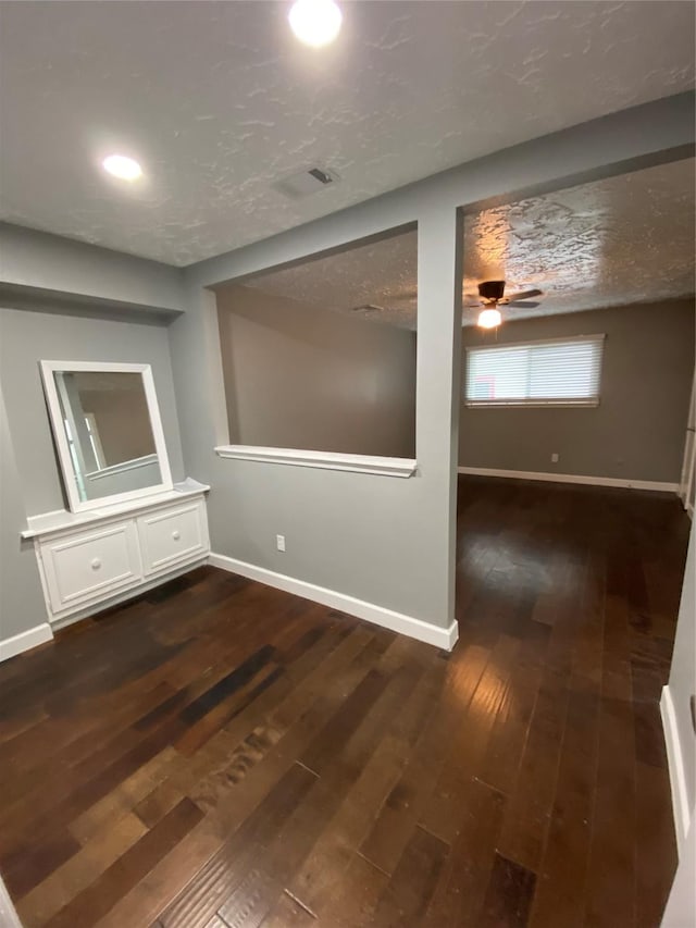 unfurnished room with ceiling fan, dark wood-type flooring, and a textured ceiling