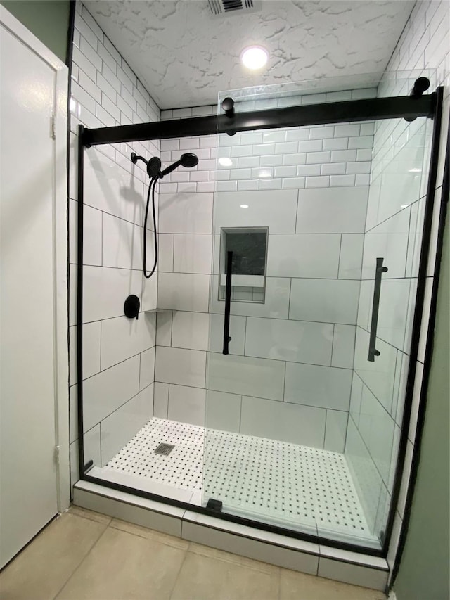 bathroom with a shower with door and tile patterned floors