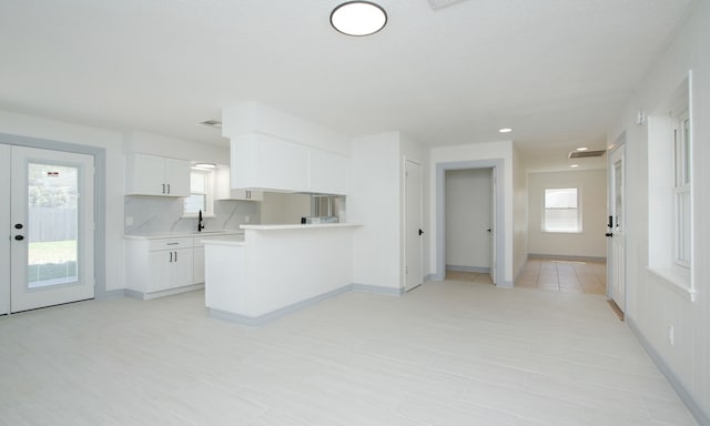 kitchen with white cabinetry, a healthy amount of sunlight, kitchen peninsula, and sink