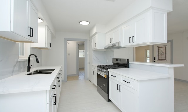 kitchen featuring stainless steel range with gas cooktop, sink, white cabinets, and kitchen peninsula