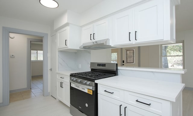 kitchen featuring a wealth of natural light, kitchen peninsula, gas stove, and white cabinets