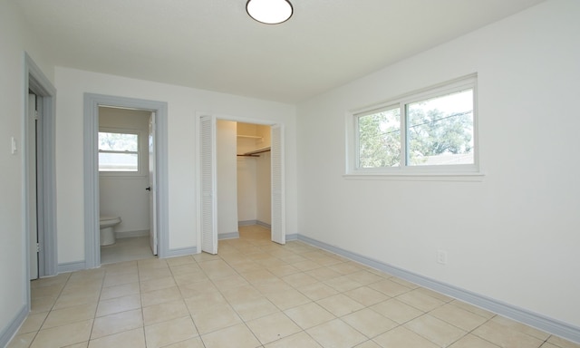 unfurnished bedroom with connected bathroom, a closet, and light tile patterned flooring