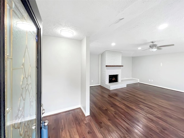 unfurnished living room featuring dark hardwood / wood-style flooring, ceiling fan, a textured ceiling, and a fireplace