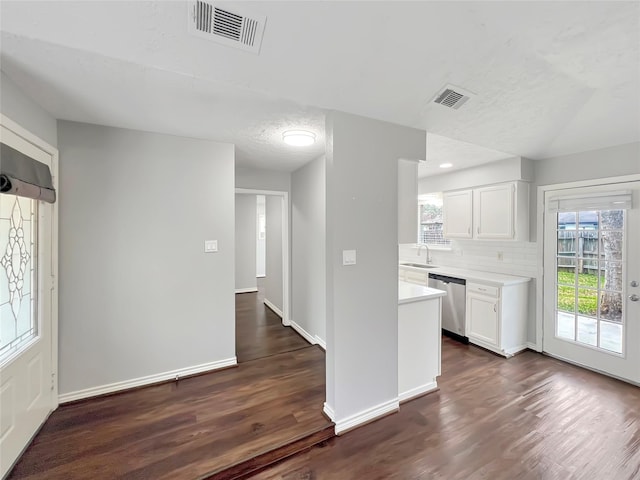 kitchen featuring white cabinetry, stainless steel dishwasher, a healthy amount of sunlight, and dark wood-type flooring