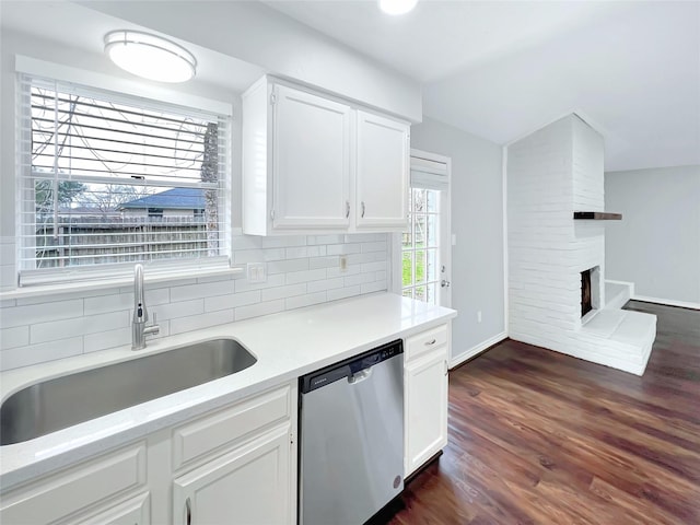 kitchen featuring a fireplace, tasteful backsplash, dishwasher, sink, and white cabinets