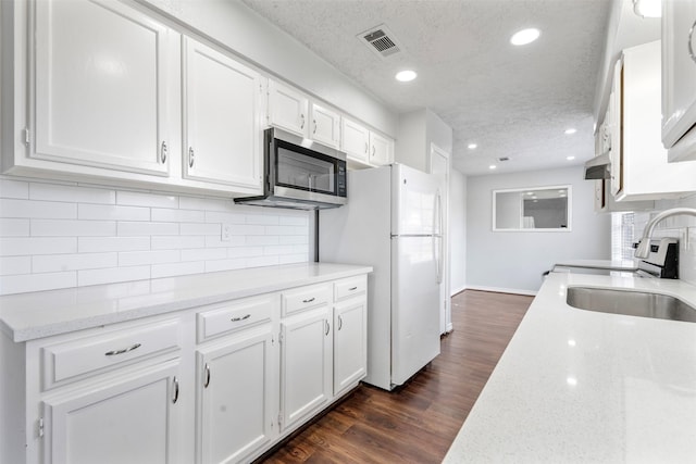 kitchen featuring stainless steel appliances, dark hardwood / wood-style floors, light stone counters, a textured ceiling, and white cabinets