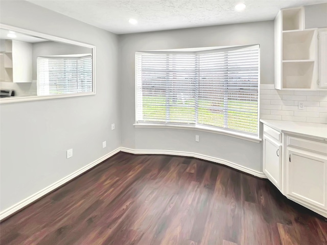 unfurnished dining area with dark hardwood / wood-style floors and a textured ceiling