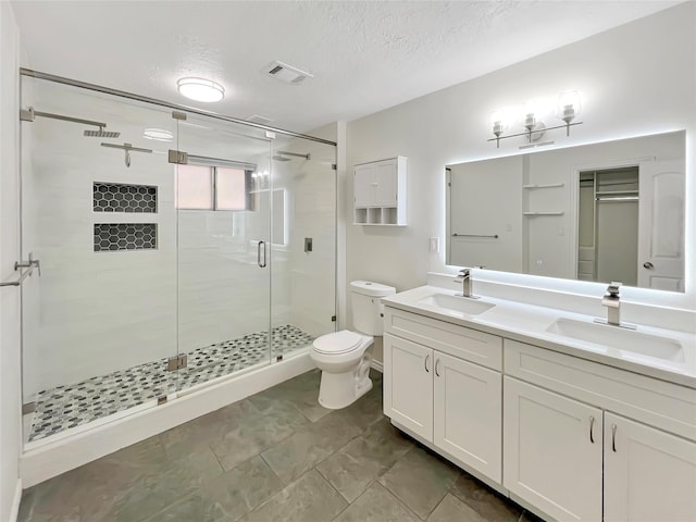 bathroom with vanity, toilet, a textured ceiling, and walk in shower