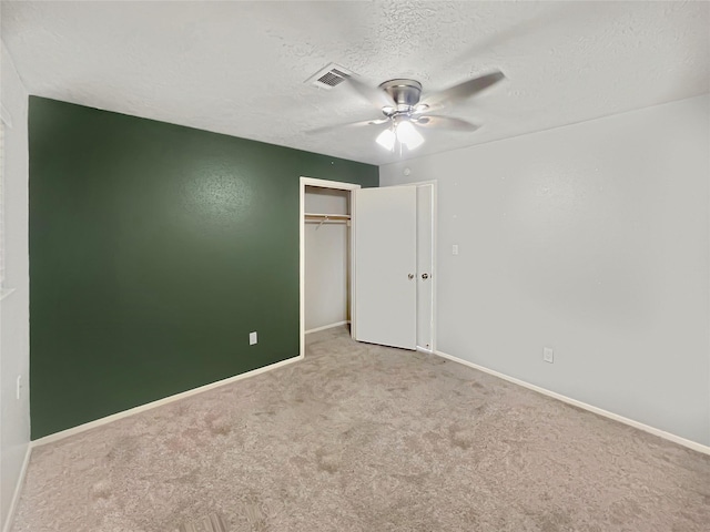 unfurnished bedroom with ceiling fan, light colored carpet, a textured ceiling, and a closet