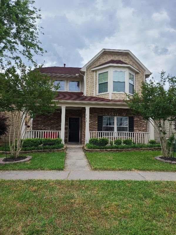 view of front of property featuring covered porch and a front lawn