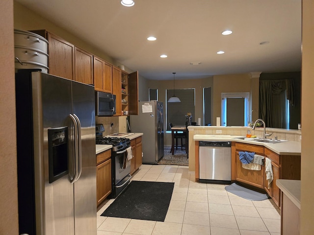 kitchen featuring a sink, black appliances, hanging light fixtures, and light countertops